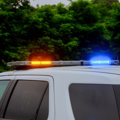 Police patrol vehicle with lights on and trees in the background